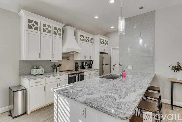 A modern kitchen with a marble countertop and stainless steel appliances.