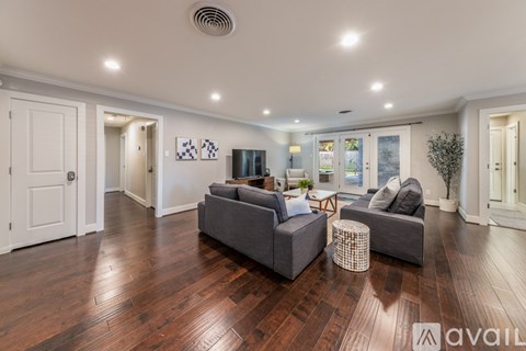 A living room with a grey couch and a wooden floor.