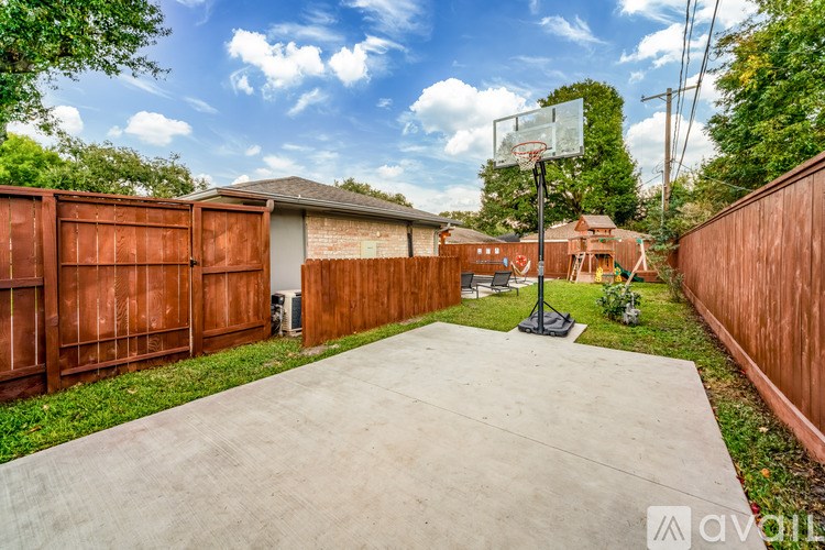 A basketball hoop stands in the middle of a concrete driveway.