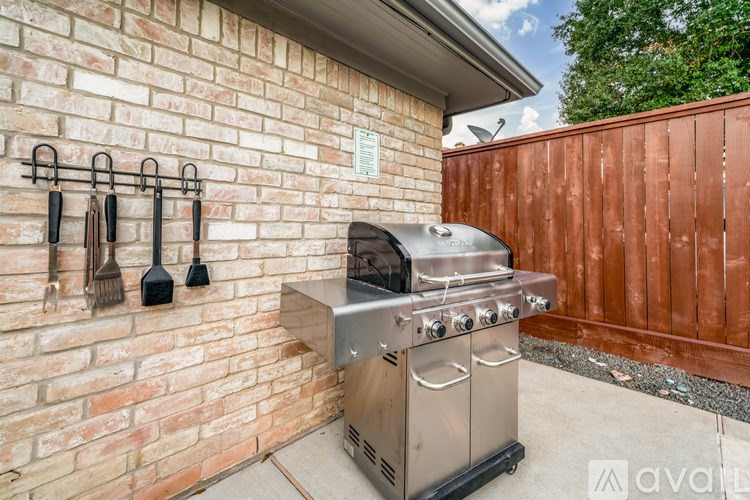 A stainless steel outdoor grill is mounted on a brick wall.
