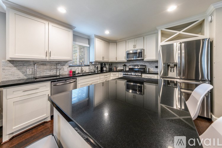 A modern kitchen with a black countertop and stainless steel appliances.