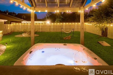 A hot tub is surrounded by lights in a backyard.
