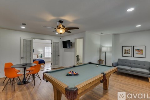 A pool table is in the middle of a room with a couch, chairs, and a television.