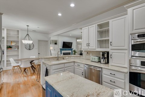 A kitchen with white cabinets and a marble countertop.
