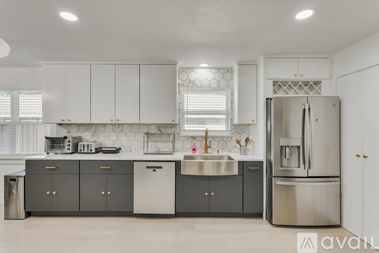 A kitchen with white cabinets and a stainless steel refrigerator.