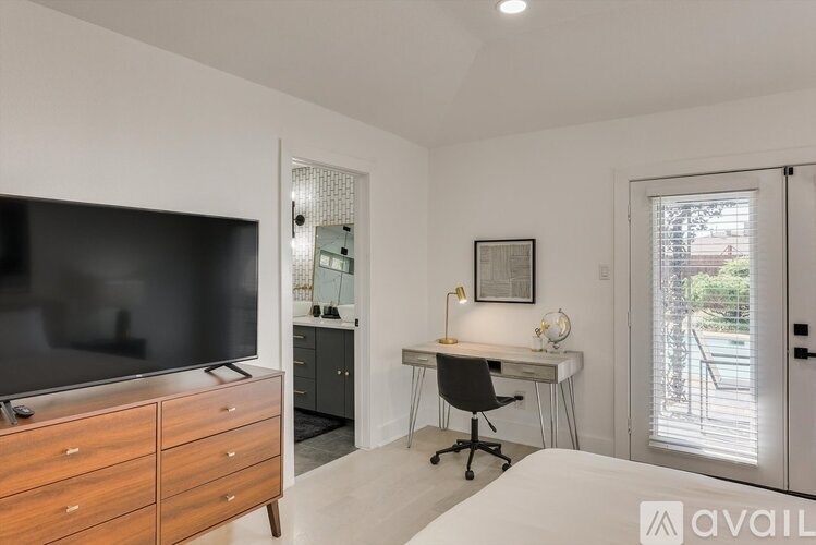 A bedroom with a bed, desk, and television.