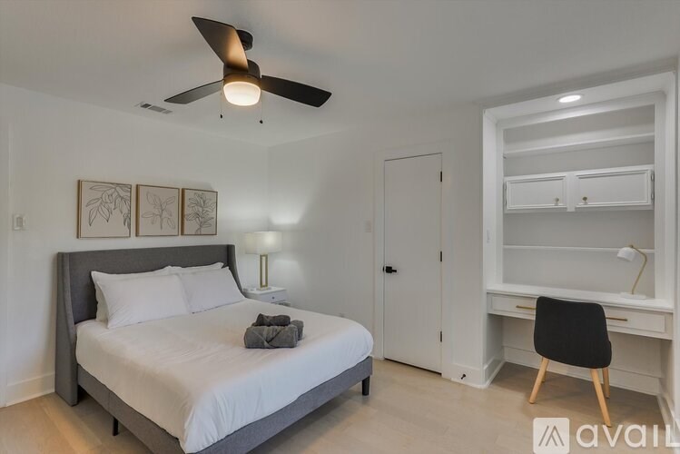 A bedroom with a bed, chair, and a ceiling fan.