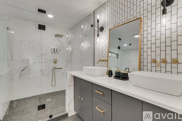 A bathroom with a marble shower and a white sink.