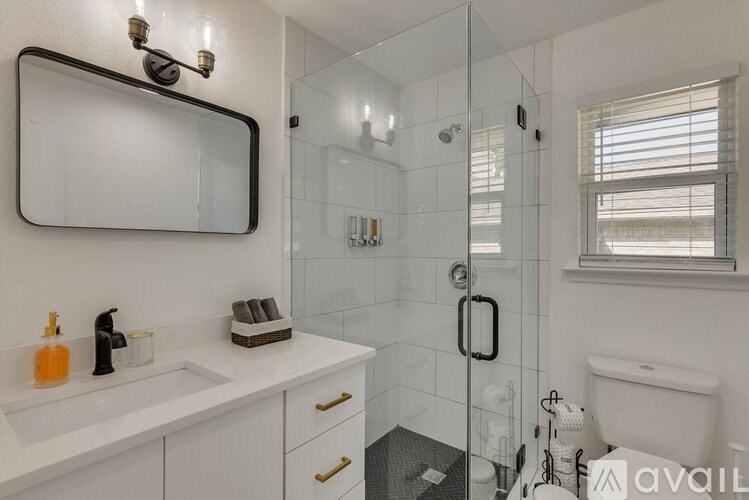 A bathroom with a white sink and a glass shower stall.