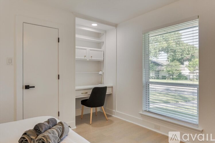 A bedroom with a white bed and a black chair.