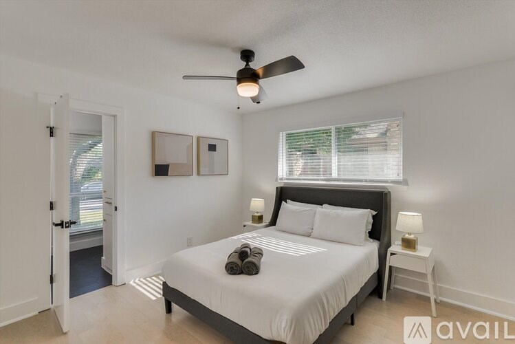 A bedroom with a bed, a ceiling fan, and a window with blinds.