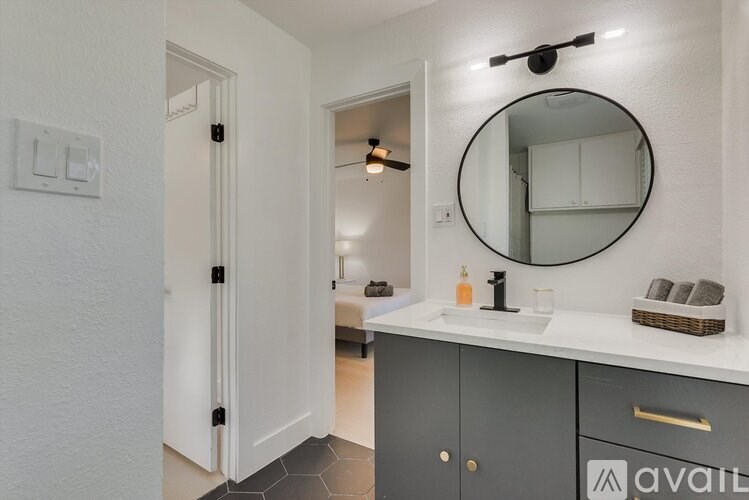 A bathroom with a white countertop and a round mirror above it.