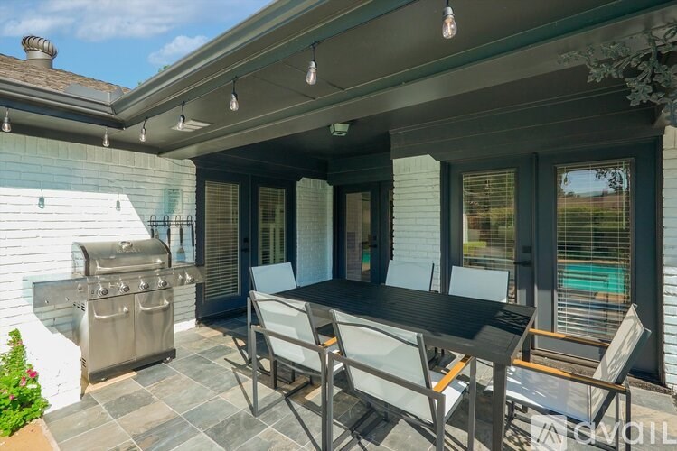 A patio with a table and chairs and a grill.