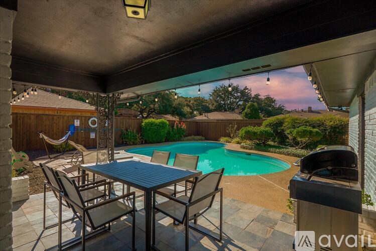 A patio with a table and chairs overlooking a pool.