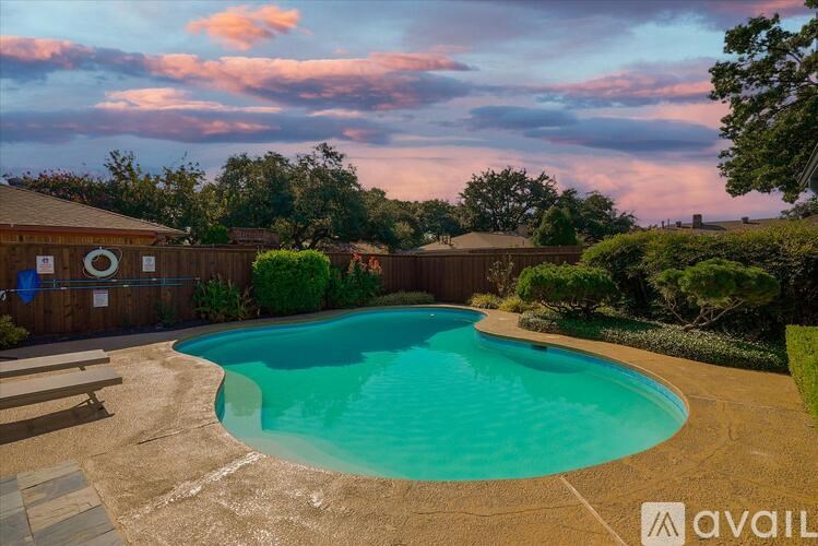 A swimming pool surrounded by a wooden fence and trees.