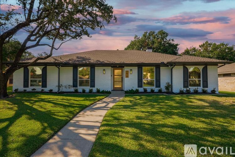 A house with a white exterior and a brown roof is shown with a sidewalk leading to the front door.