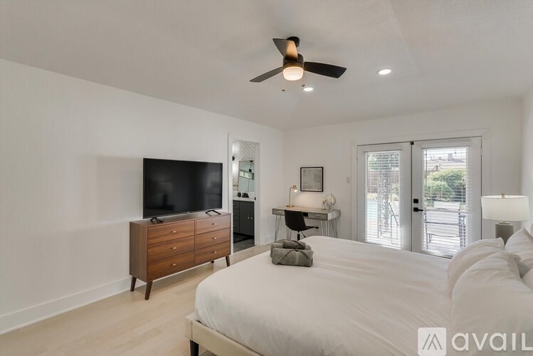 A bedroom with a large bed, a flat screen TV, and a ceiling fan.