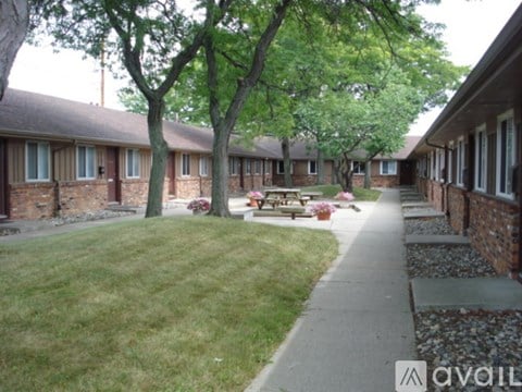 A grassy area in front of a building with a tree and a bench.
