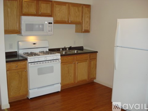 A kitchen with a white fridge, white stove and white microwave.