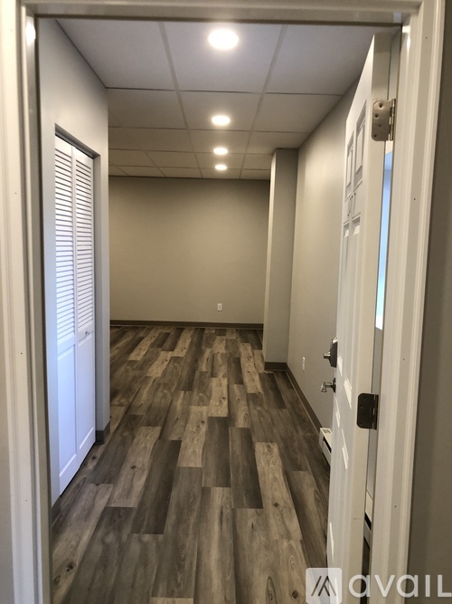 A hallway with wood flooring and white walls.