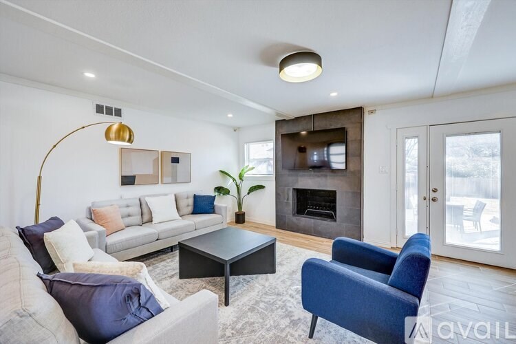 A living room with a grey couch, a blue armchair, and a fireplace.