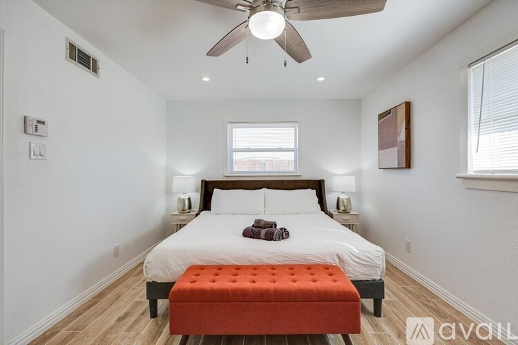 A bedroom with a bed, a ceiling fan, and a window.