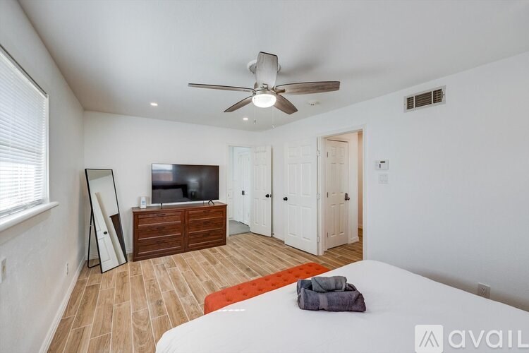A bedroom with a bed, dresser, and television.