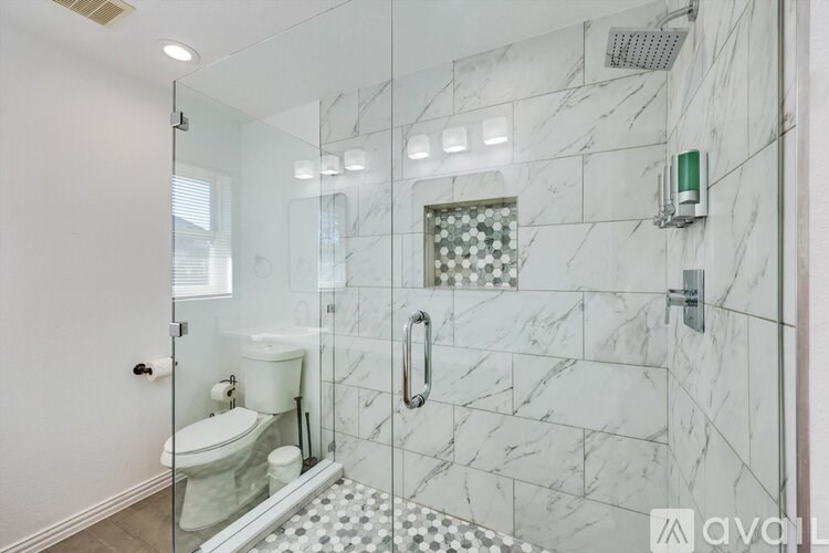 A bathroom with a marble tile shower and a glass door.