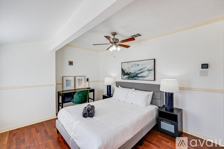 A bedroom with a bed, nightstand, and a ceiling fan.