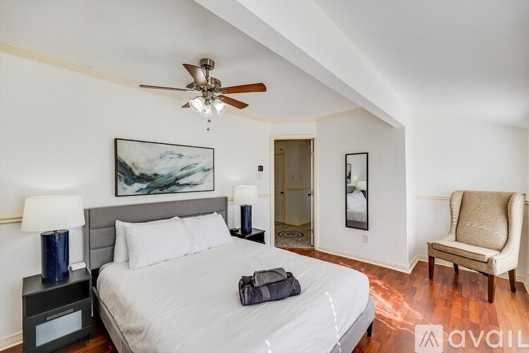 A bedroom with a bed, chair, and painting on the wall.