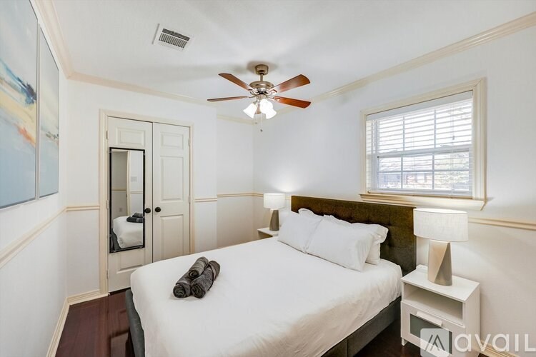 A bedroom with a bed, a ceiling fan, and a window.