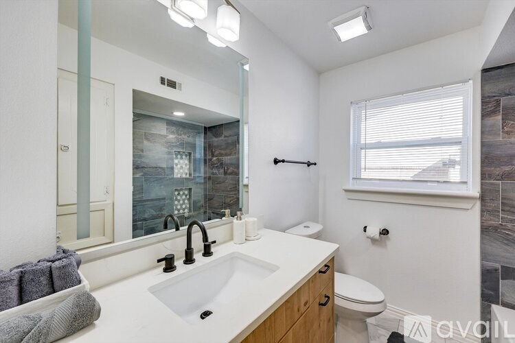 A bathroom with a sink, toilet, and a window.