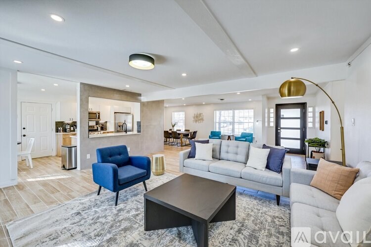 A modern living room with a blue armchair and a grey sofa.