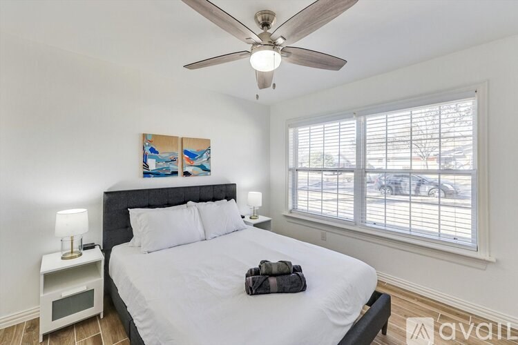 A bedroom with a bed, a ceiling fan, and a window with blinds.