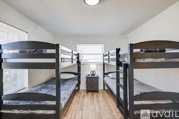 A room with two bunk beds and a nightstand.