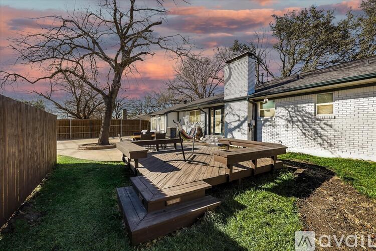 A backyard with a wooden deck and patio furniture.