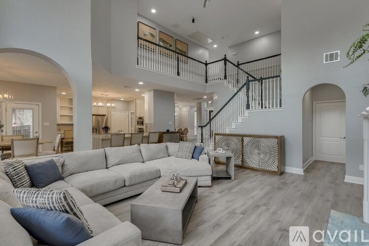 A spacious living room with a grey sofa and a wooden coffee table.