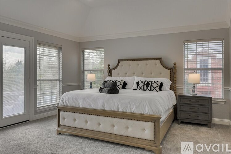 A bedroom with a large bed, a nightstand, and a window with blinds.