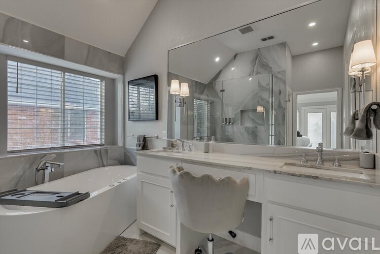 A bathroom with a large mirror, a bathtub, and a sink.