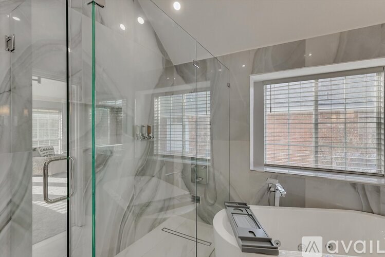 A modern bathroom with a glass shower enclosure and a white bathtub.