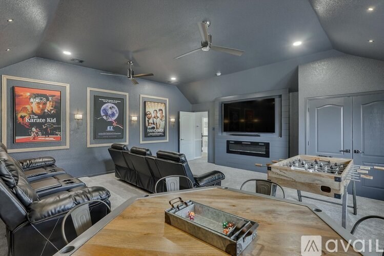A living room with a black leather couch, a wooden coffee table, and a flat screen TV mounted on the wall.