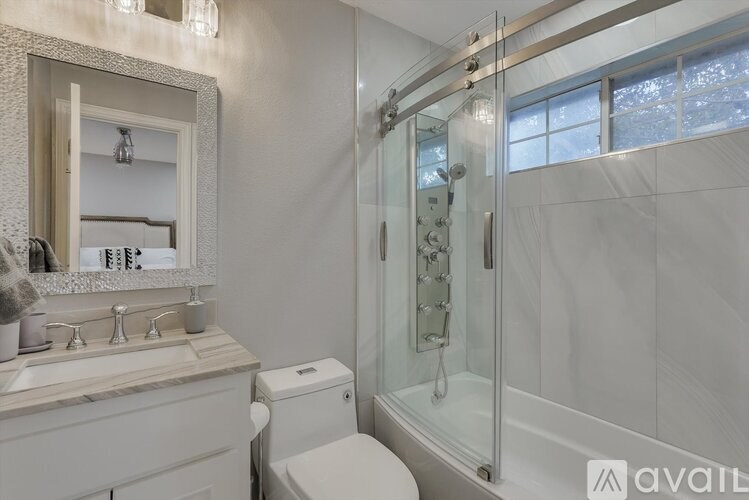 A bathroom with a toilet, sink, mirror, and shower.