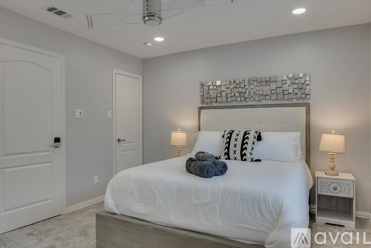 A bedroom with a large bed and two lamps.