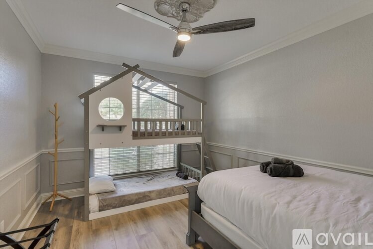 A bedroom with a bed, a window with blinds, and a ceiling fan.