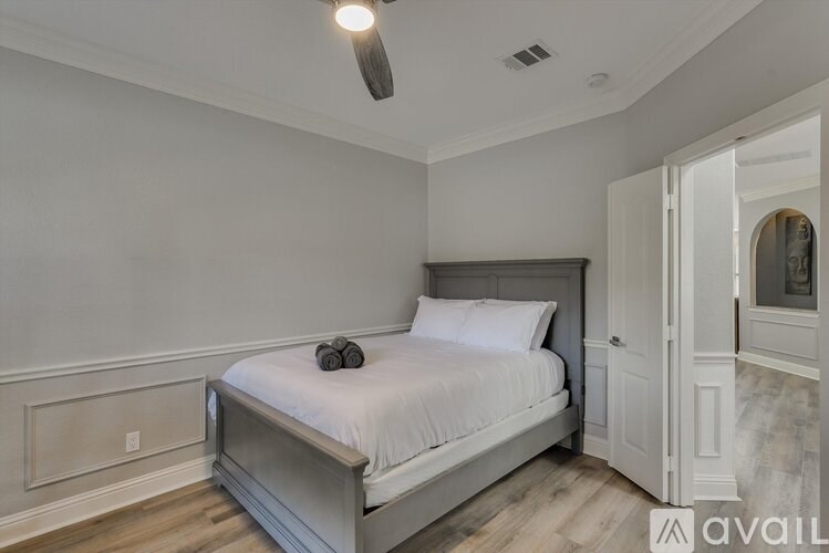A bedroom with a bed, a ceiling fan, and a doorway leading to another room.