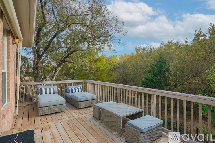 A wooden deck with two chairs and two ottomans.