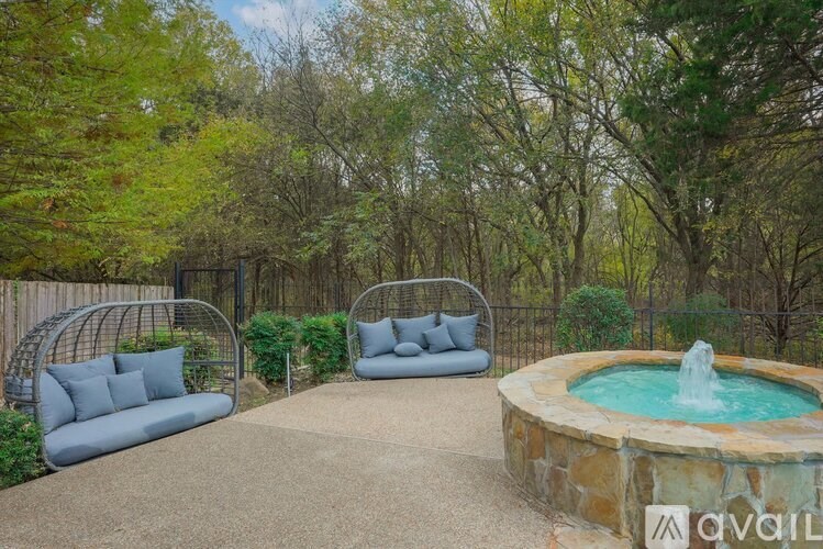 A backyard with a fountain, two chairs and a bench.