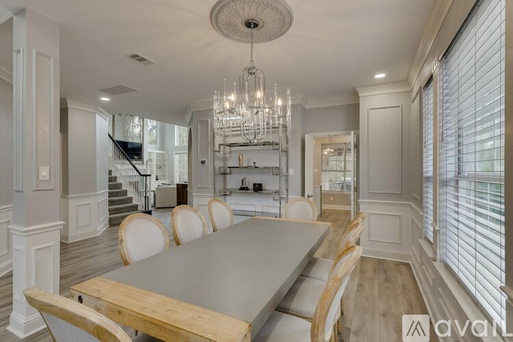 A dining room with a large table and chairs.