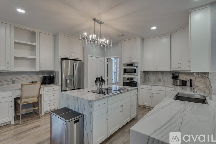 A modern kitchen with white cabinets and a marble countertop.