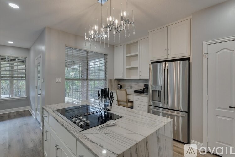 A modern kitchen with a marble countertop and stainless steel appliances.